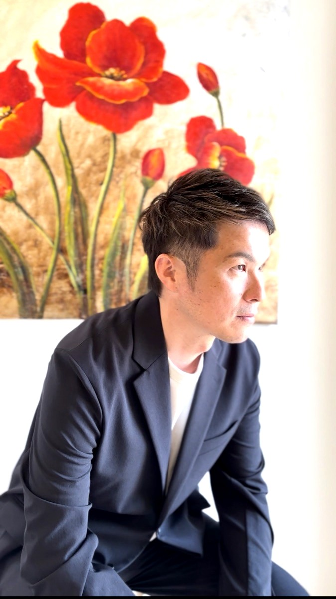 横顔で相手の話に耳を傾けている原口卓也の写真